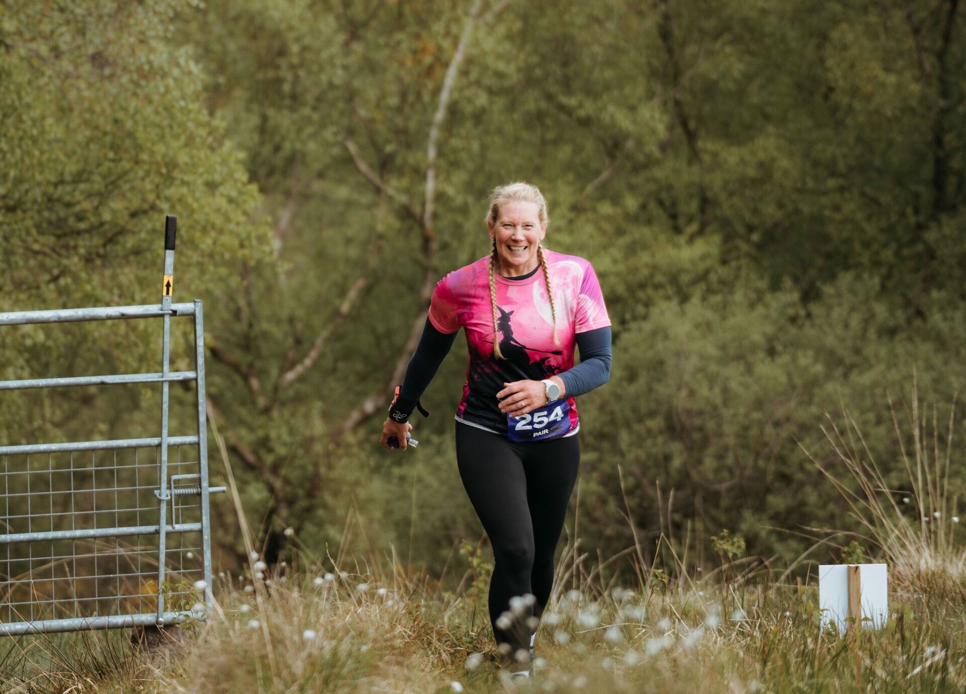 Runner in pink witch tee climbing past a metal gate