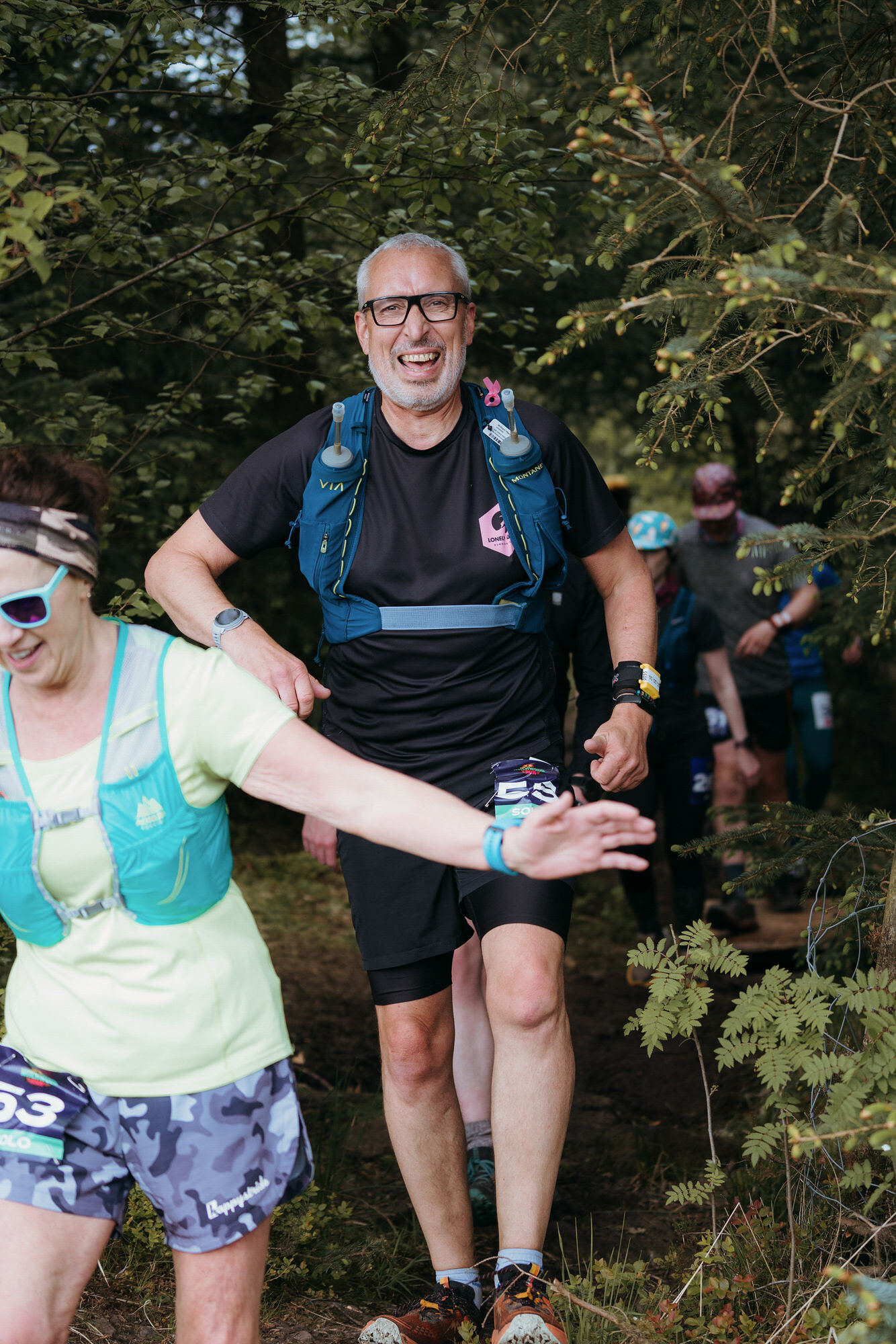 Grinning runner in glasses and Montane vest in the woods