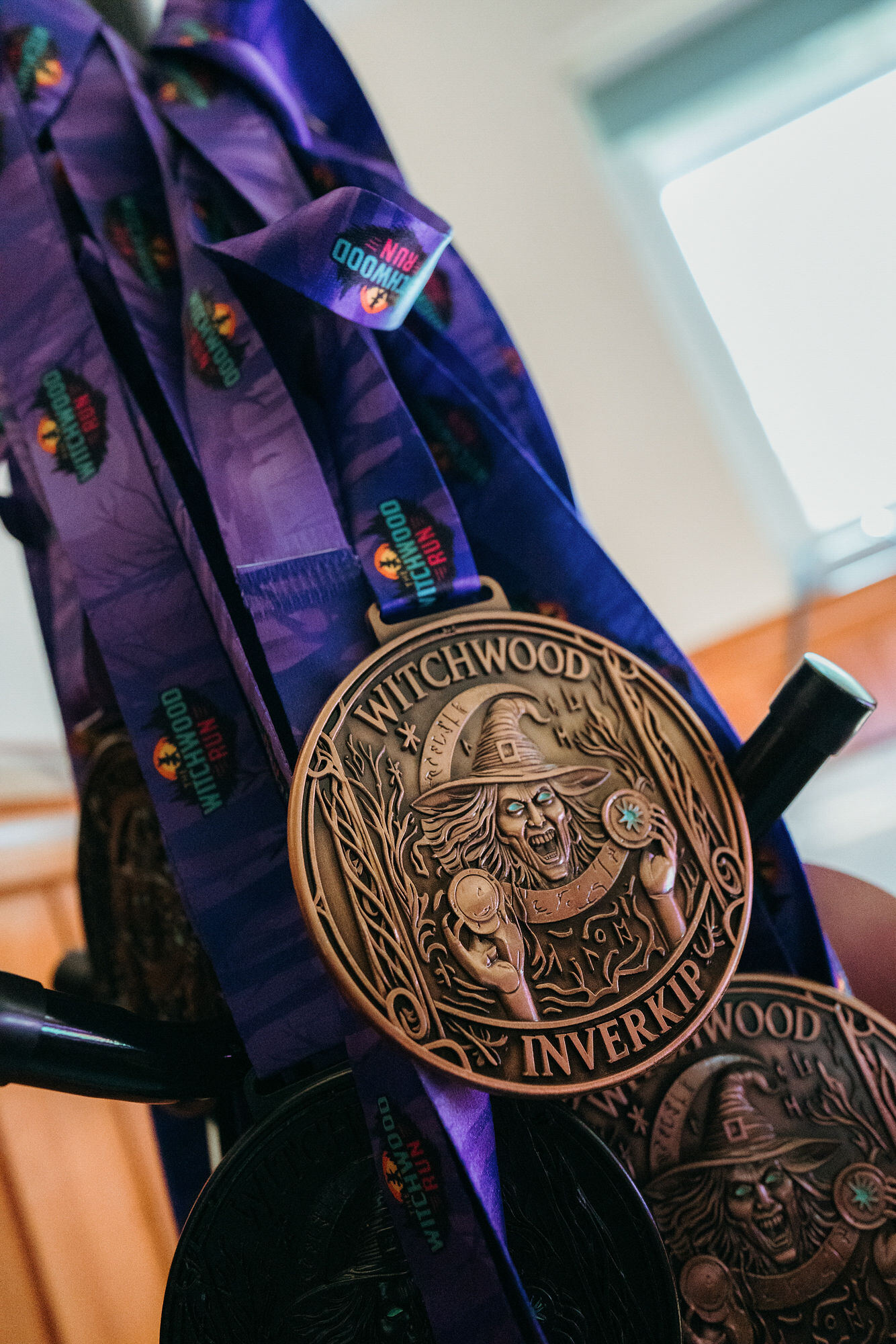 Witchwood Run medal — bronze witch design on a purple lanyard