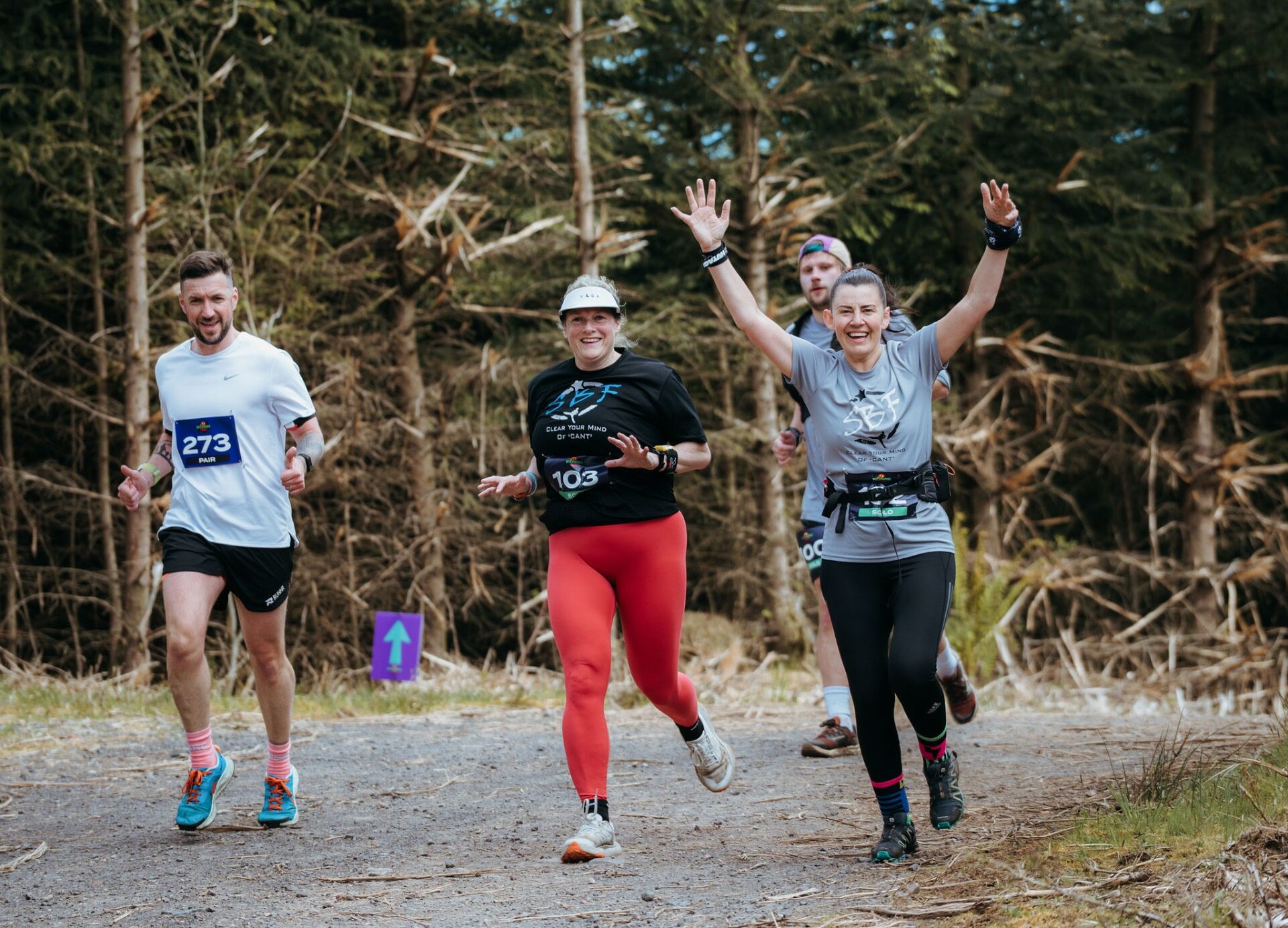 Three runners celebrating with arms in the air in the forest