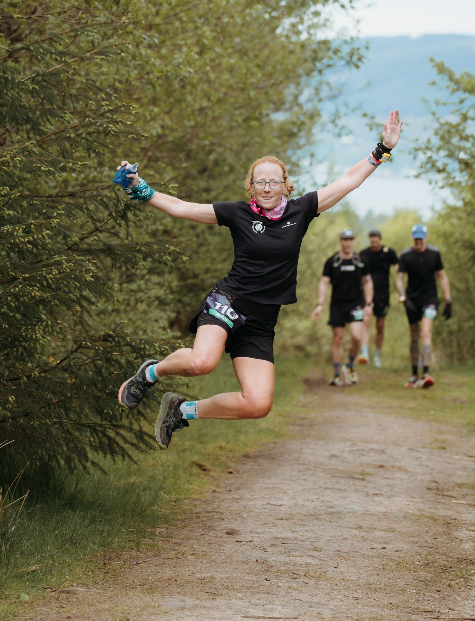 Runner mid-air on the trail, firth in the distance