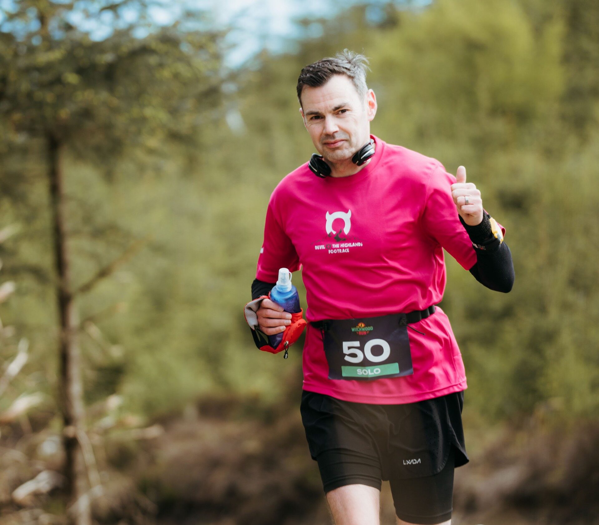 Solo runner number 50 giving a thumbs up on the forest path
