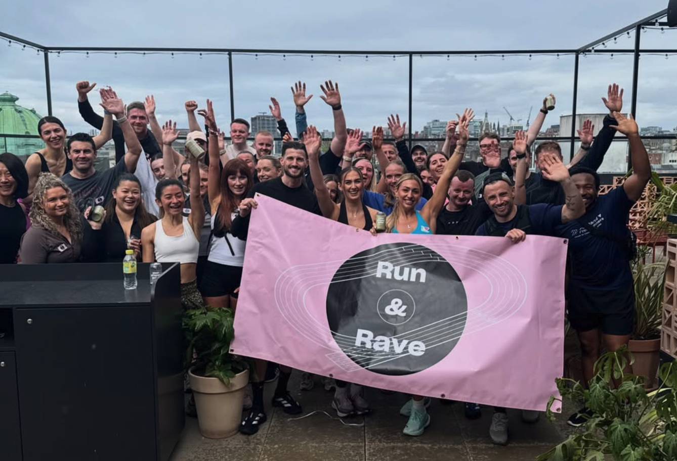 G1 Run group photo on the Social Hub rooftop behind a pink Run & Rave banner