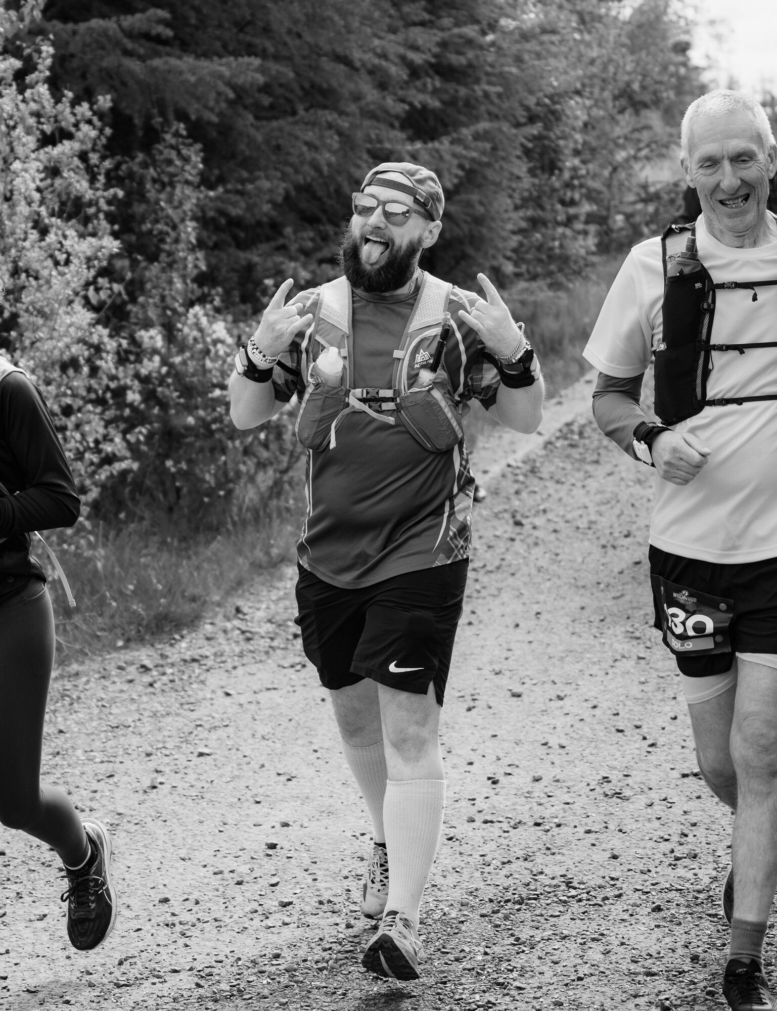Black and white shot of bearded runner throwing rock-on hands mid-race