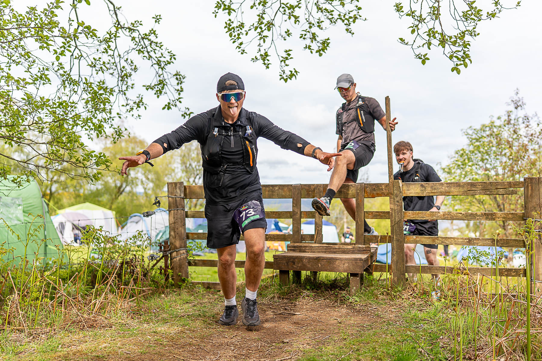Runner clearing a stile at Witchwood Run, tongue out