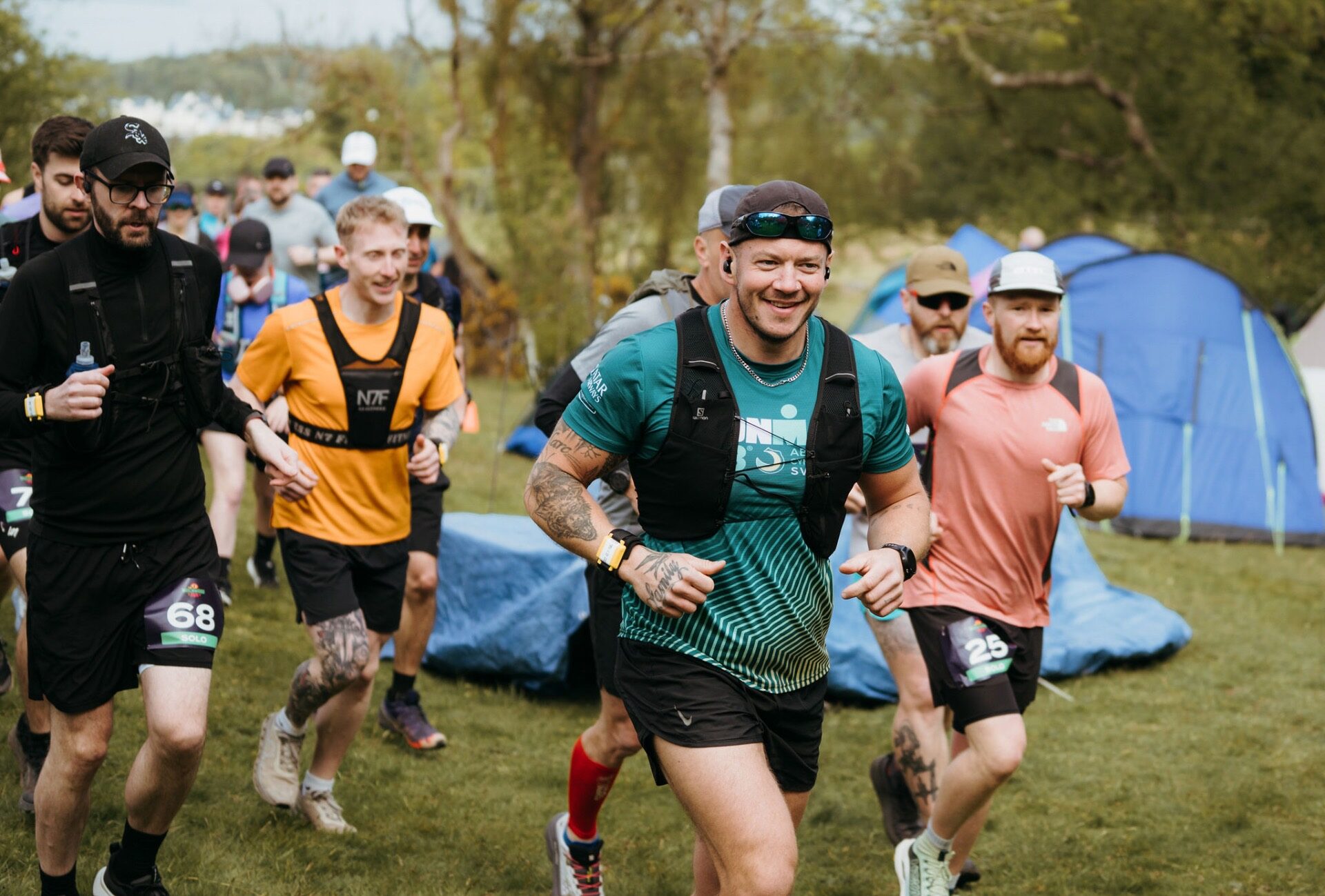 Smiling runner leading the pack past tents at the start
