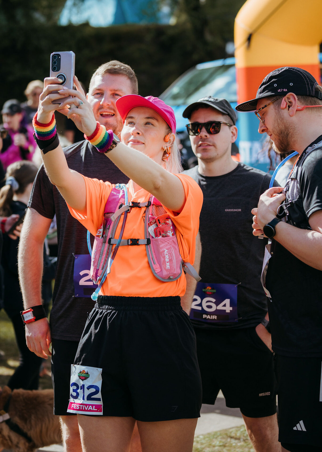 Runner in orange taking a selfie at the start line with the festival arch behind